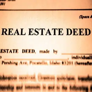 Close-up of a real estate deed document with the title 'REAL ESTATE DEED' highlighted in focus.
