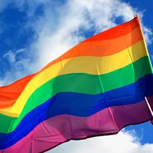 Vibrant pride flag against clouds, showcasing LGBTQ+ community support.